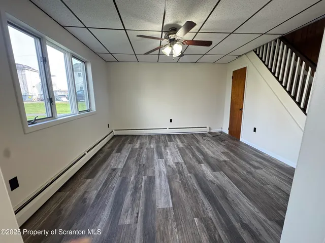 a view of a room with wooden floor fan and windows