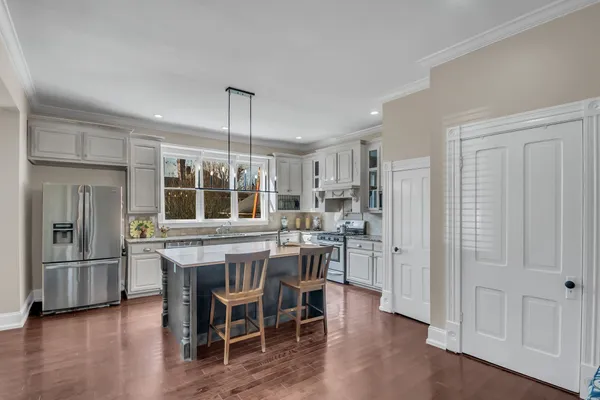 a kitchen with stainless steel appliances granite countertop a dining table chairs refrigerator and sink