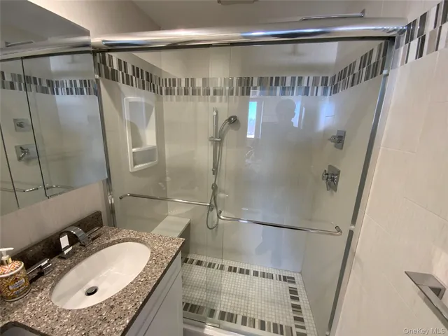 a bathroom with a granite countertop shower sink vanity and a mirror