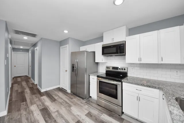 a kitchen with stainless steel appliances granite countertop a stove a refrigerator and a microwave oven