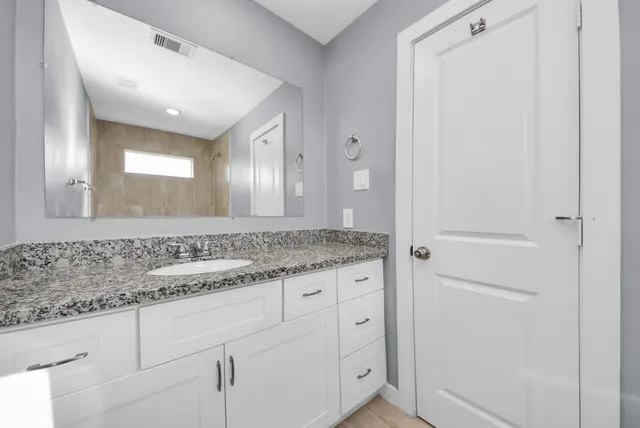 a bathroom with a granite countertop sink and a mirror