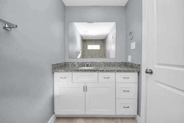 a bathroom with a granite countertop sink and a mirror