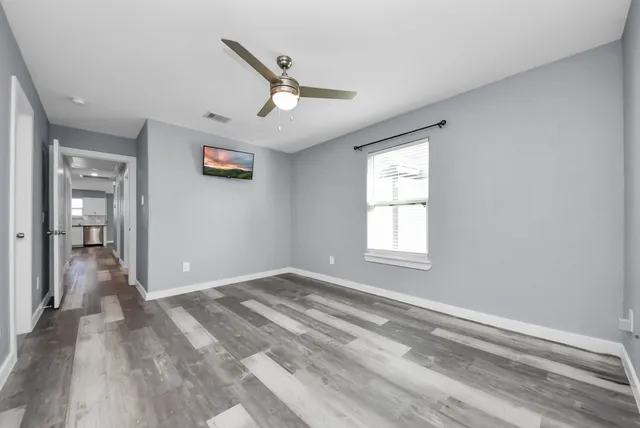 a view of empty room with wooden floor and fan