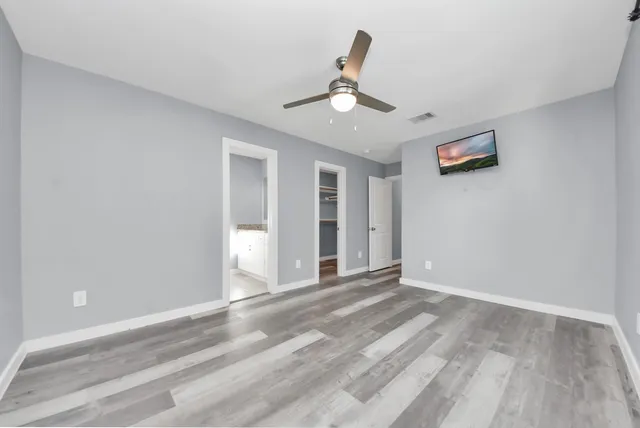a view of an empty room with window and chandelier fan