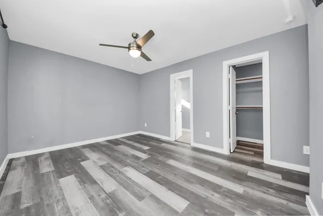 a view of empty room with wooden floor and ceiling fan