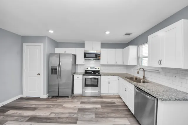 a kitchen with stainless steel appliances granite countertop a sink stove and refrigerator