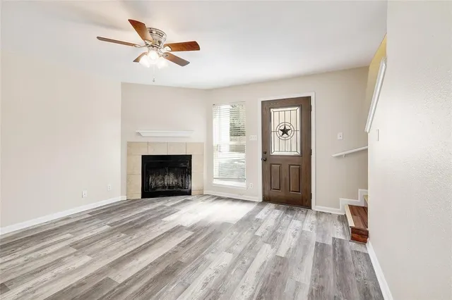 a view of a livingroom with a fireplace a ceiling fan and wooden floor