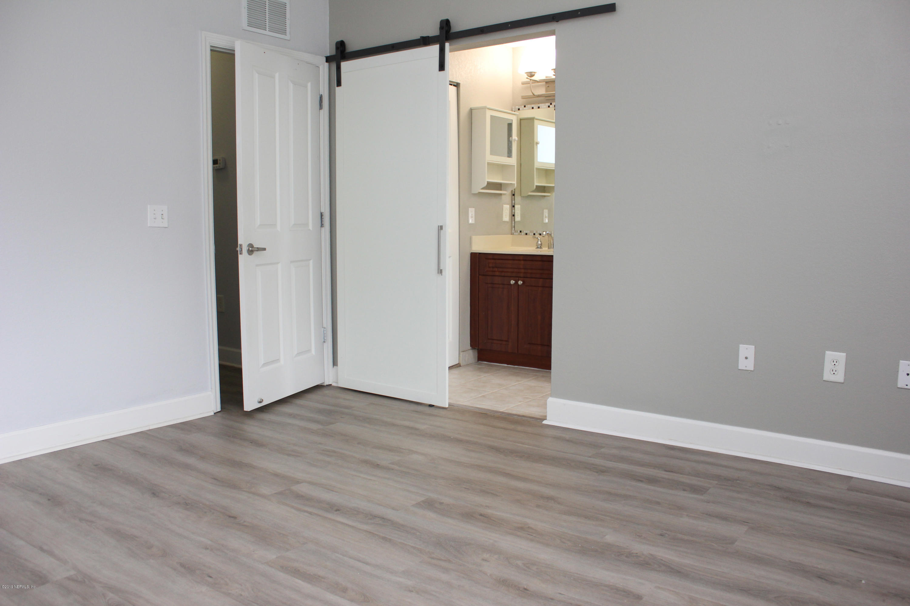 9745 Touchton Road, Unit 1323 Jacksonville, FL 32246 - Photo 11 of 19 a view of an empty room with wooden floor and a bathroom