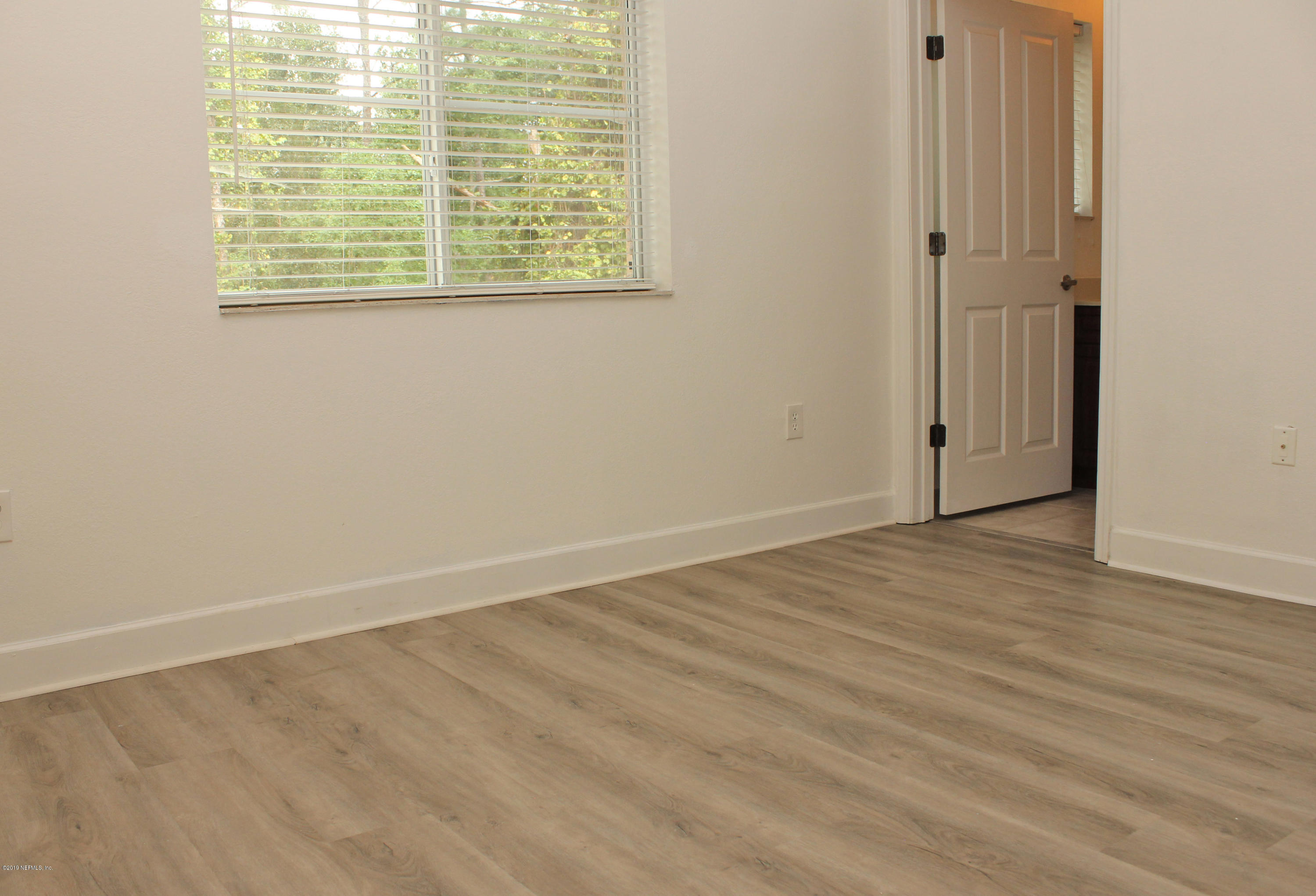 9745 Touchton Road, Unit 1323 Jacksonville, FL 32246 - Photo 15 of 19 an empty room with wooden floor and windows