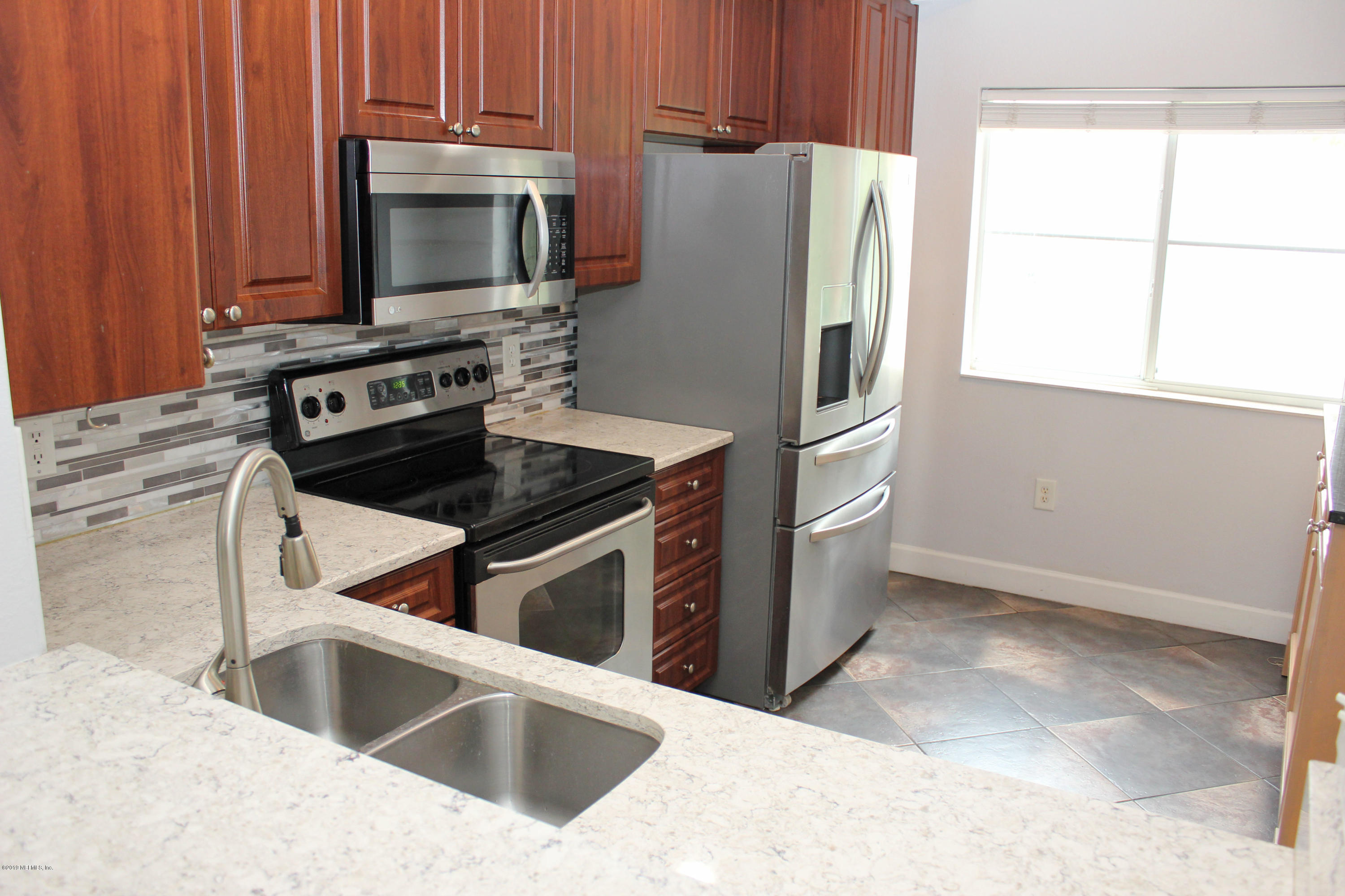9745 Touchton Road, Unit 1323 Jacksonville, FL 32246 - Photo 3 of 19 a kitchen with granite countertop a refrigerator stove and microwave