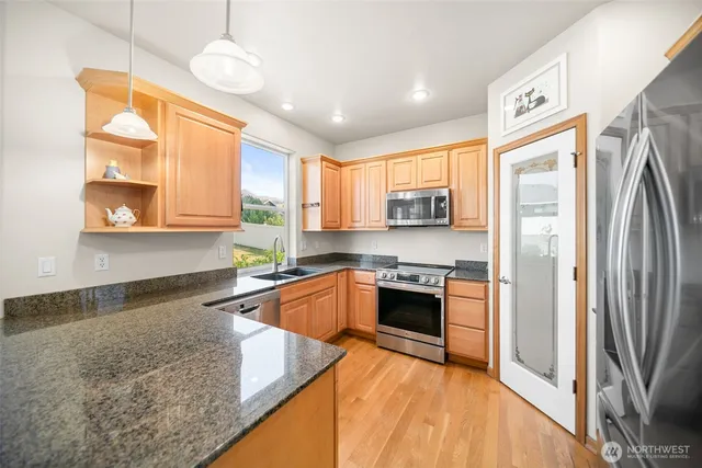 a large kitchen with stainless steel appliances granite countertop a refrigerator and a sink