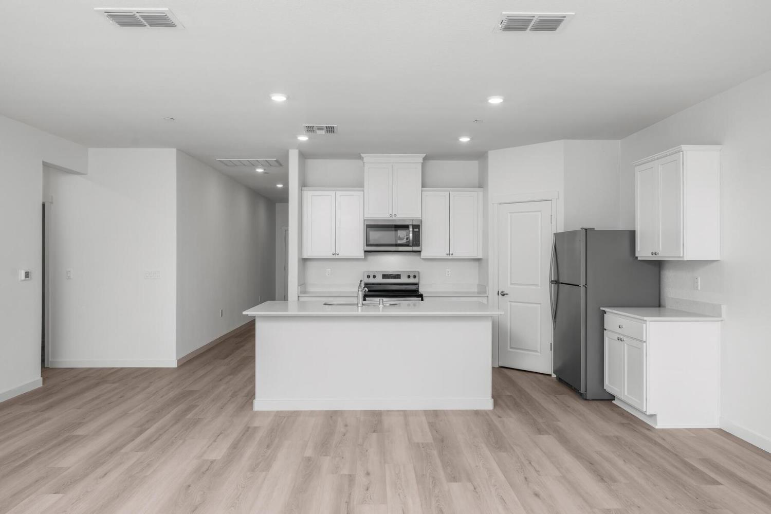 2199 Nicklaus Drive Linda, CA 95901 - Photo 14 of 16 a large kitchen with stainless steel appliances granite countertop a stove top oven a refrigerator and a white cabinets with wooden floor