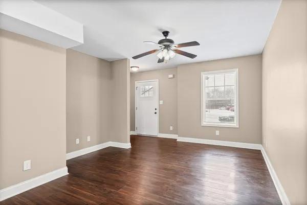 a view of an empty room with wooden floor and a window