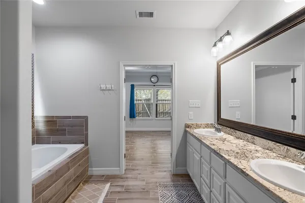a bathroom with a granite countertop tub a sink and a large mirror