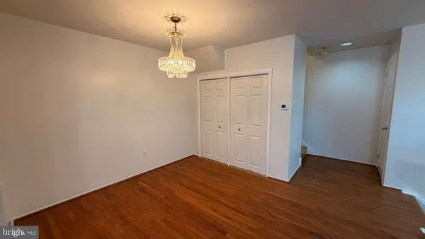 an empty room with wooden floor and chandelier