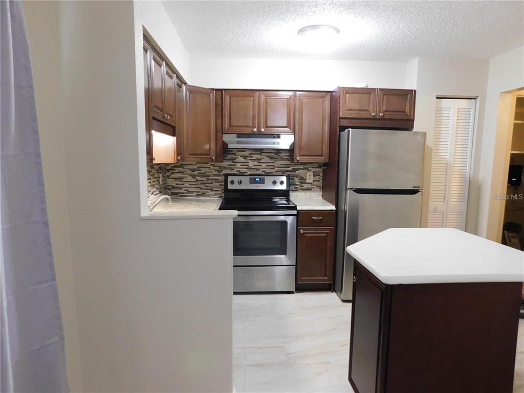 21150 Gertrude Avenue, Unit B4 Port Charlotte, FL 33952 - Photo 5 of 10 a kitchen with stainless steel appliances a refrigerator stove and microwave