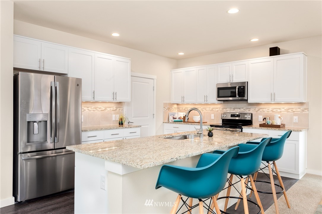 443 Partlon Street, Unit 75 Buckley, WA 98321 - Photo 6 of 25 a kitchen with stainless steel appliances granite countertop a refrigerator a stove a sink a dining table and chairs