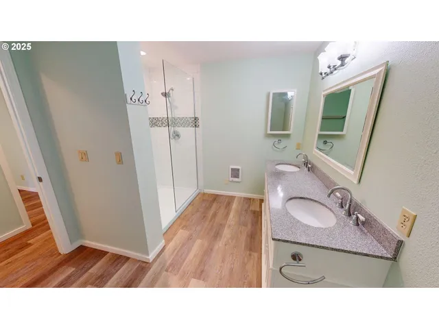 a bathroom with a sink double vanity granite tub shower and a mirror