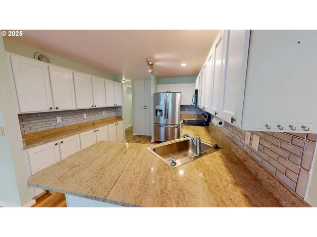 a living room with stainless steel appliances kitchen island granite countertop a sink and cabinets