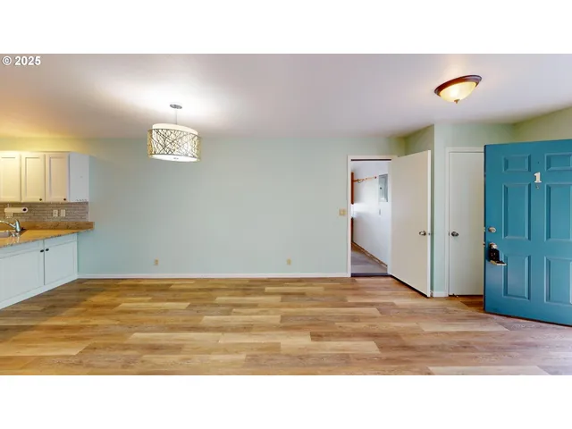 a view of kitchen and empty room with wooden floor