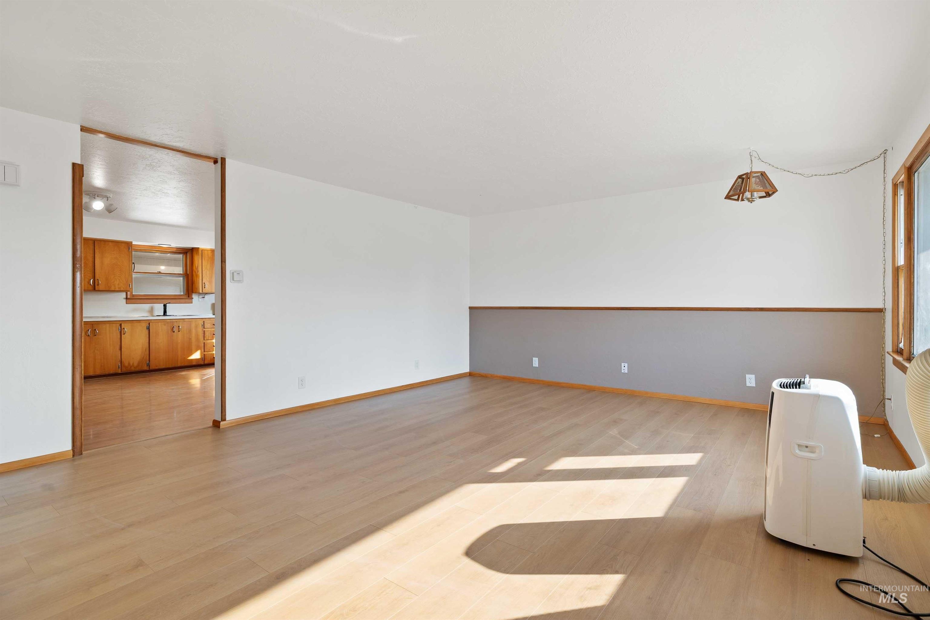 321 Clear Lakes Road Buhl, ID 83316 - Photo 4 of 34 Wood-finish flooring throughout, white walls with a gray accent, wood trim, and a window with wood framing