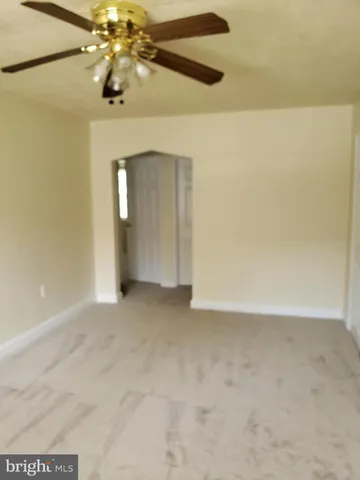 a view of an empty room with a chandelier fan