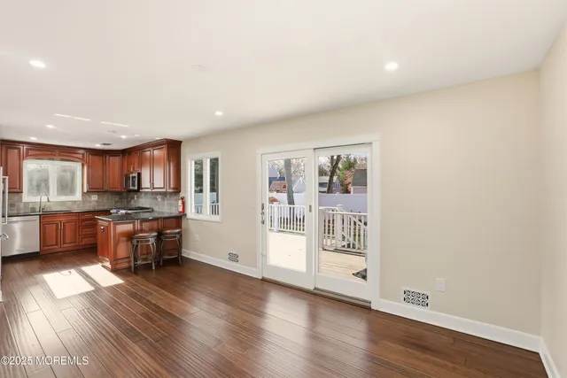 a large living room with stainless steel appliances wooden floor and a large window