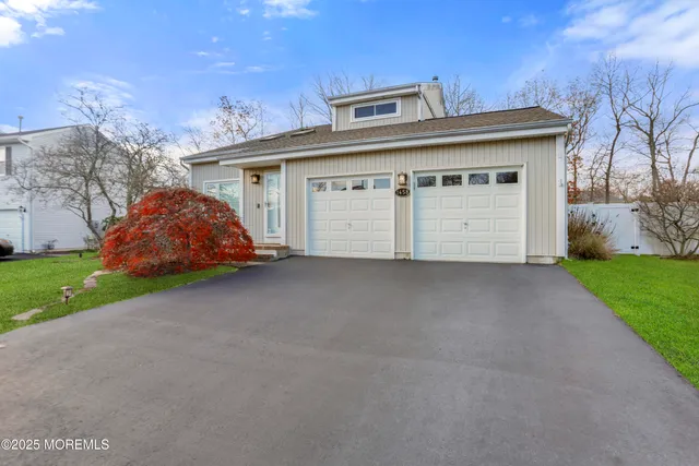 a view of a white house with a small yard and a large parking space