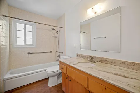 a bathroom with a granite countertop sink a toilet and shower
