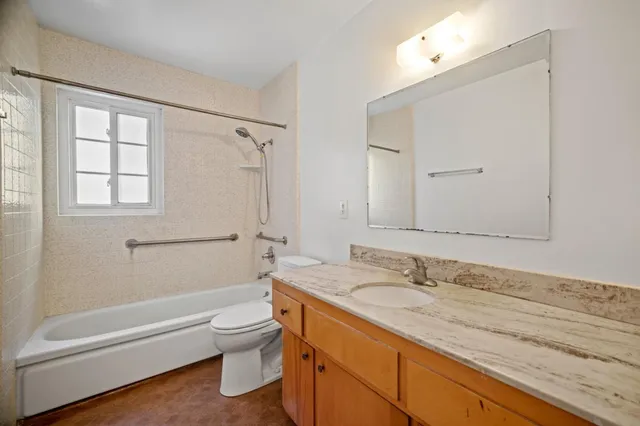 a bathroom with a granite countertop sink a toilet and shower