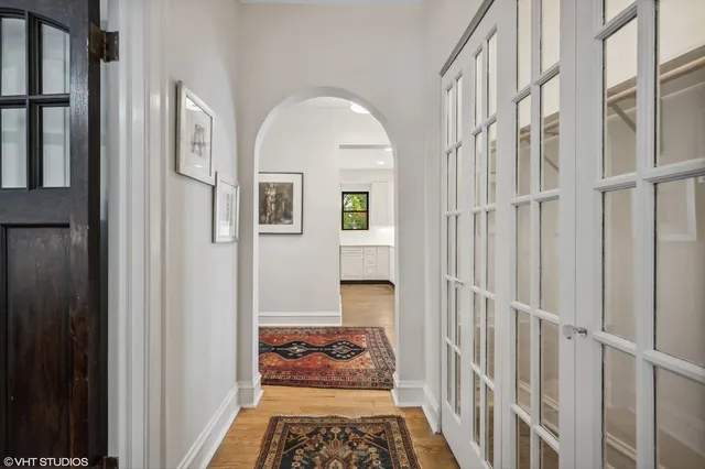 a hallway with wooden floor a chandelier and a window
