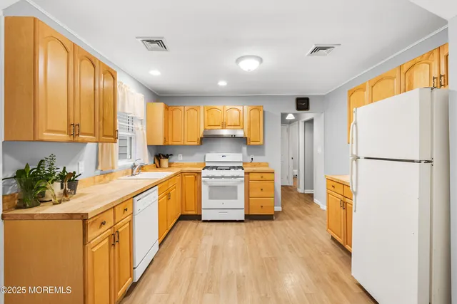 a kitchen with stainless steel appliances granite countertop a refrigerator a stove top oven a sink and dishwasher with wooden floor