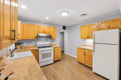 a kitchen with granite countertop wooden floors a stove a sink and a refrigerator