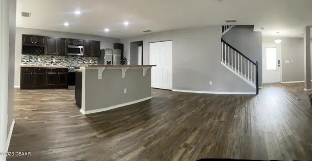 a view of an empty room with window and chandelier fan