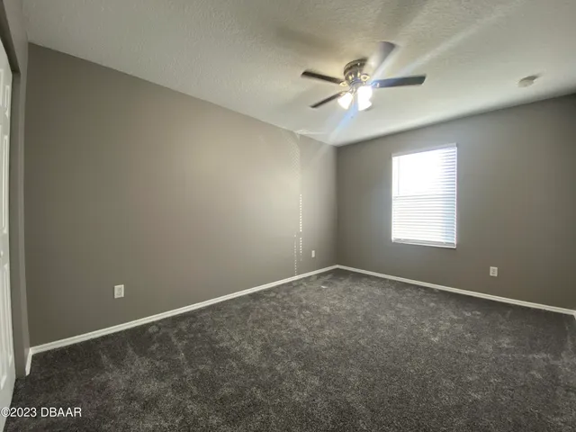 an empty room with closet and a ceiling fan