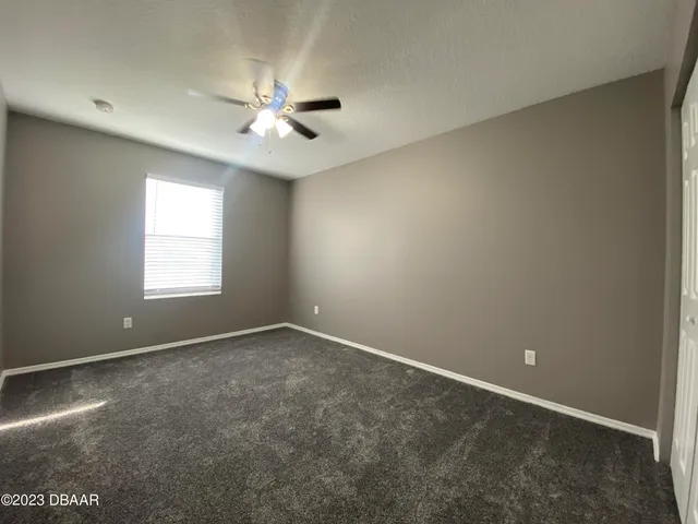 an empty room with a ceiling fan and a window