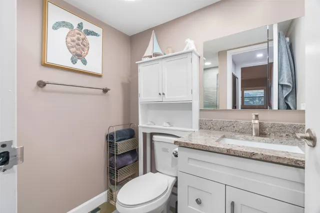 a bathroom with a granite countertop toilet sink and mirror