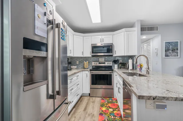 a kitchen with stainless steel appliances granite countertop a sink refrigerator and microwave