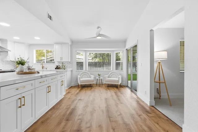 a large white kitchen with a large window a refrigerator and a sink