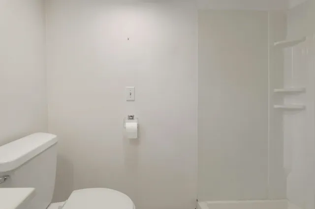 a white toilet sitting next to a white wall