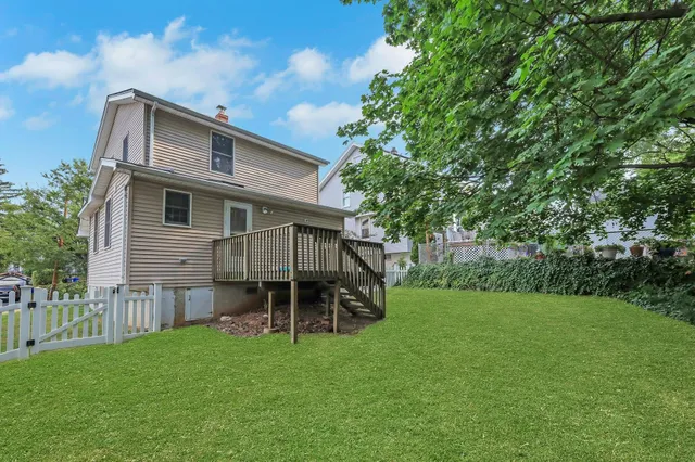 a backyard of a house with wooden fence and large trees