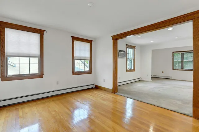 a view of an empty room with window and wooden floor