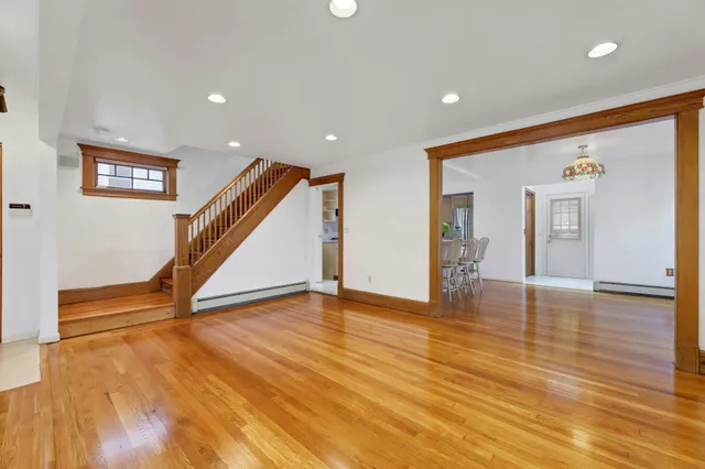 a view of an empty room with wooden floor and stairs