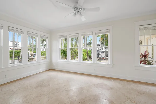 an empty room with windows and chandelier fan
