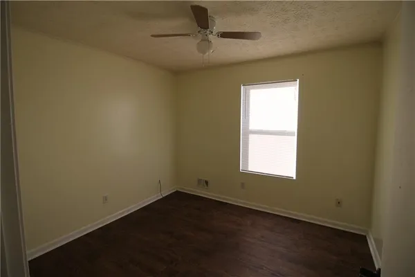 an empty room with a window and a fan