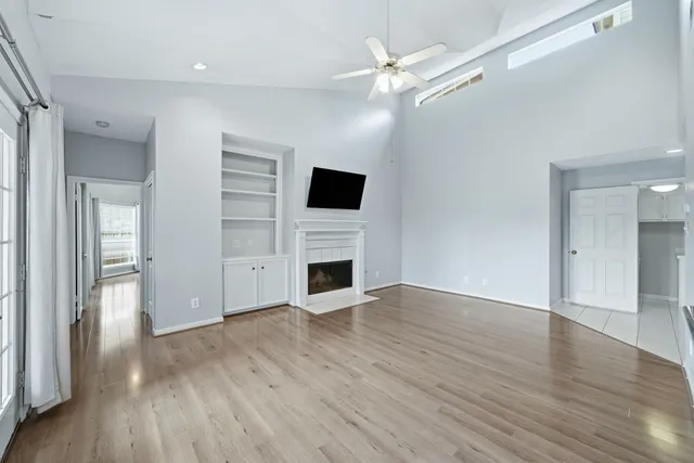 an empty room with wooden floor fireplace and windows