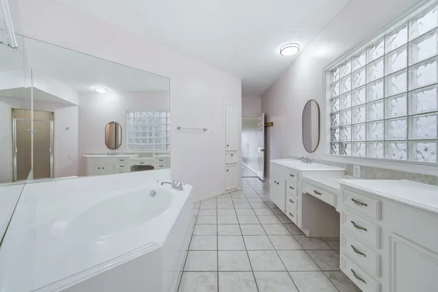 a large bathroom with a double vanity sink a mirror and a bathtub