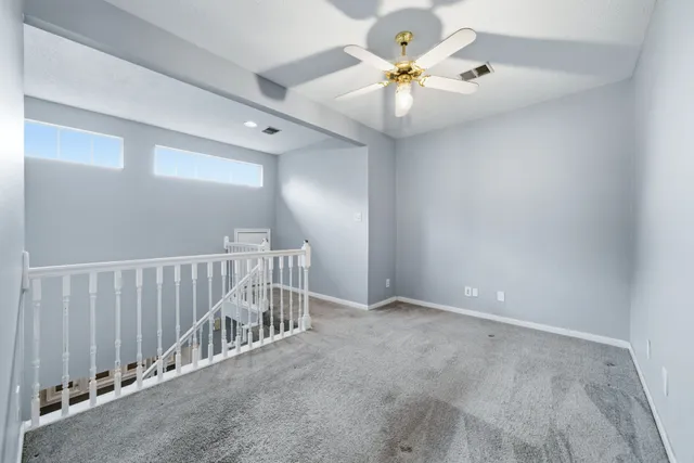 a view of an empty room with a chandelier fan