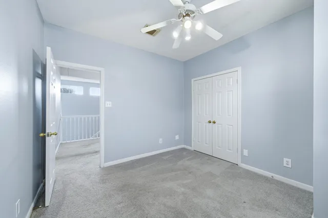 an empty room with closet and a chandelier fan
