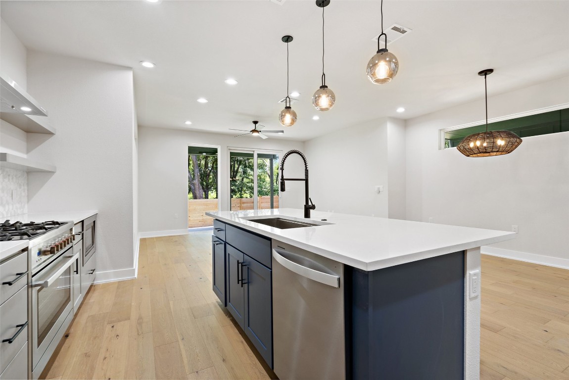 5109 Stone Gate Drive, Unit 2 Austin, TX 78721 - Photo 1 of 38 a kitchen with a stove a sink a kitchen island with wooden floor and cabinets